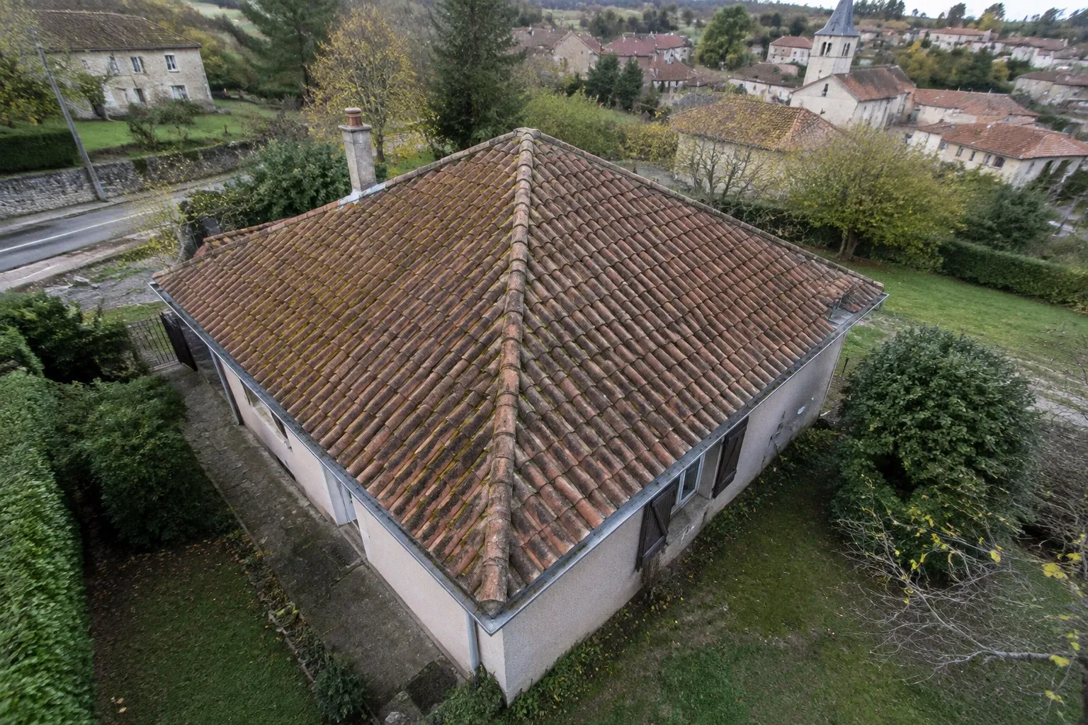 Toit en tuiles couvert de mousse vu depuis un drone, village en arrière-plan